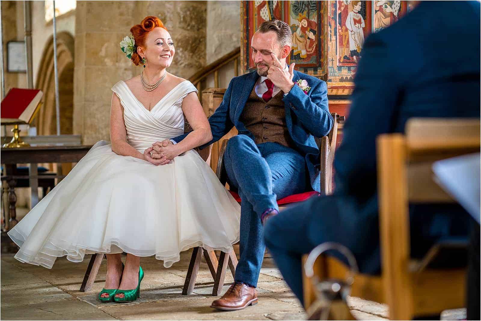 bride smiling at groom whilst he wipes a tear away - best wedding photography in warwickshire 2019