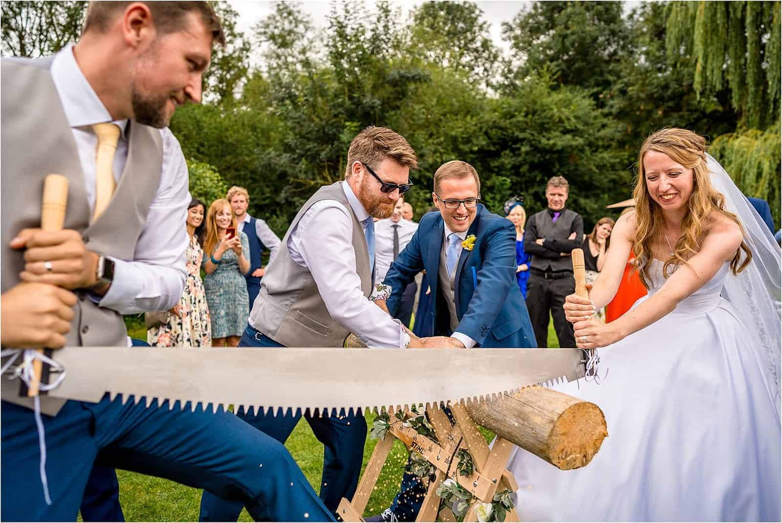 bride and groom sawing a log as a german tradition - best wedding photography in warwickshire 2019