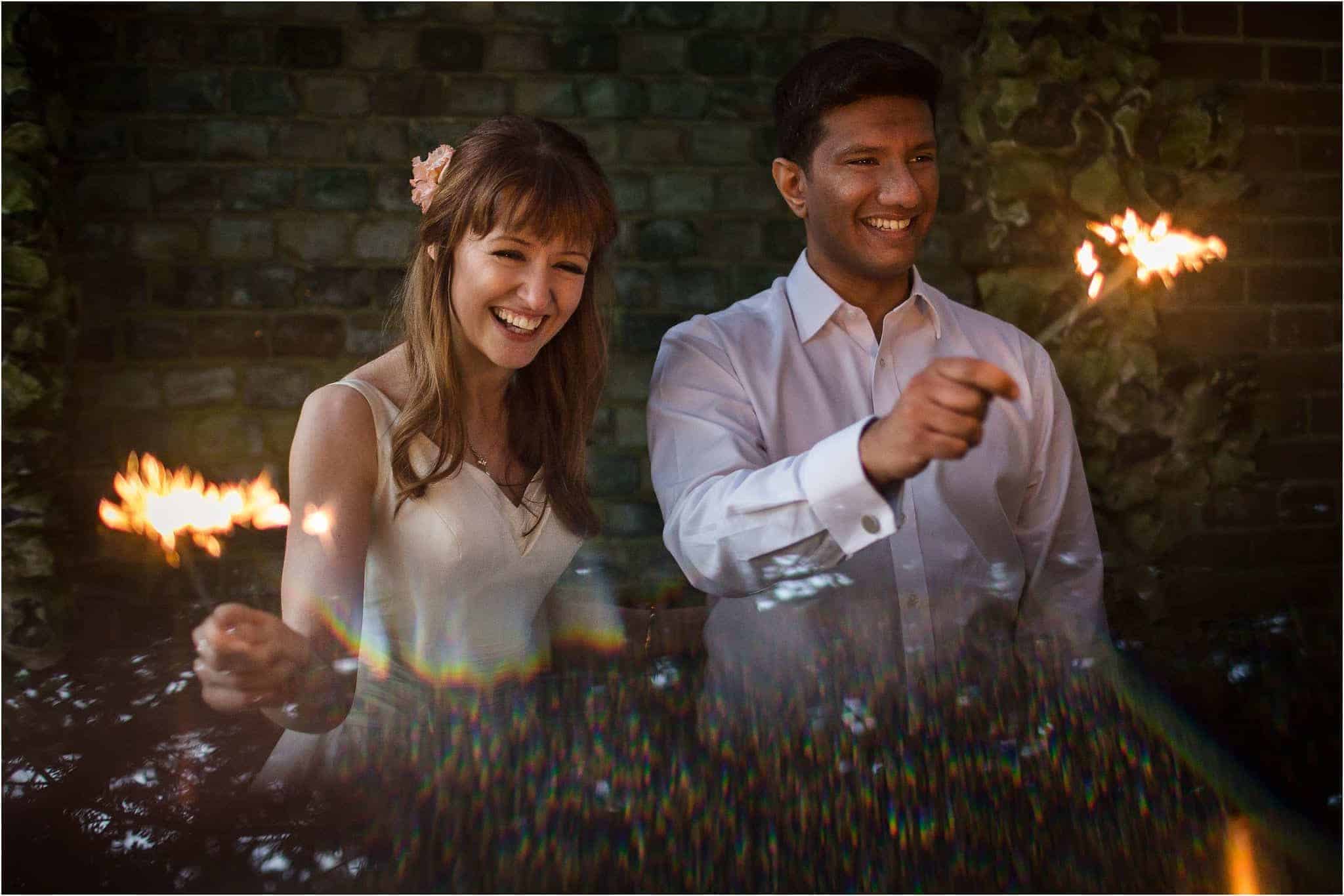 A bride and groom playing with sparklers on their wedding day. Image by S2 Images, Hampden House Wedding Photographer