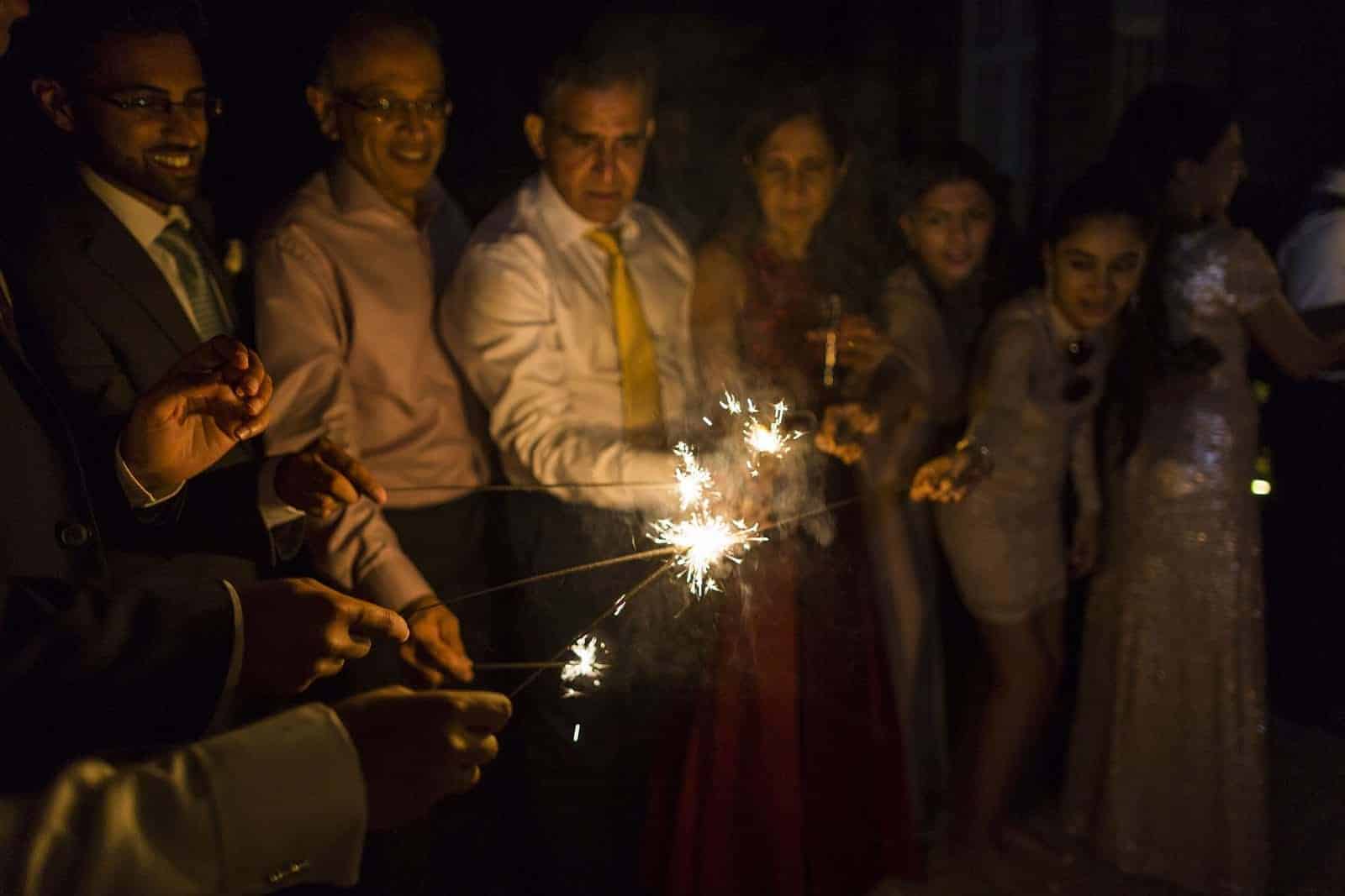 guests preparing for sparkler tunnel by lighting sparklers